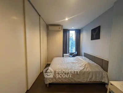 Modern bedroom with stylish decor and city view, featuring a comfortable bed and ample storage space.
