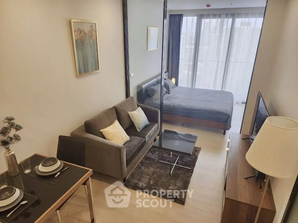 Modern studio apartment with cozy living area and stylish bedroom, featuring floor-to-ceiling windows.