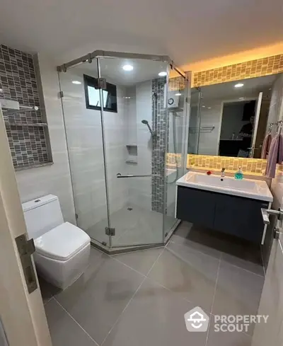 Modern bathroom with glass shower and stylish vanity in contemporary apartment.