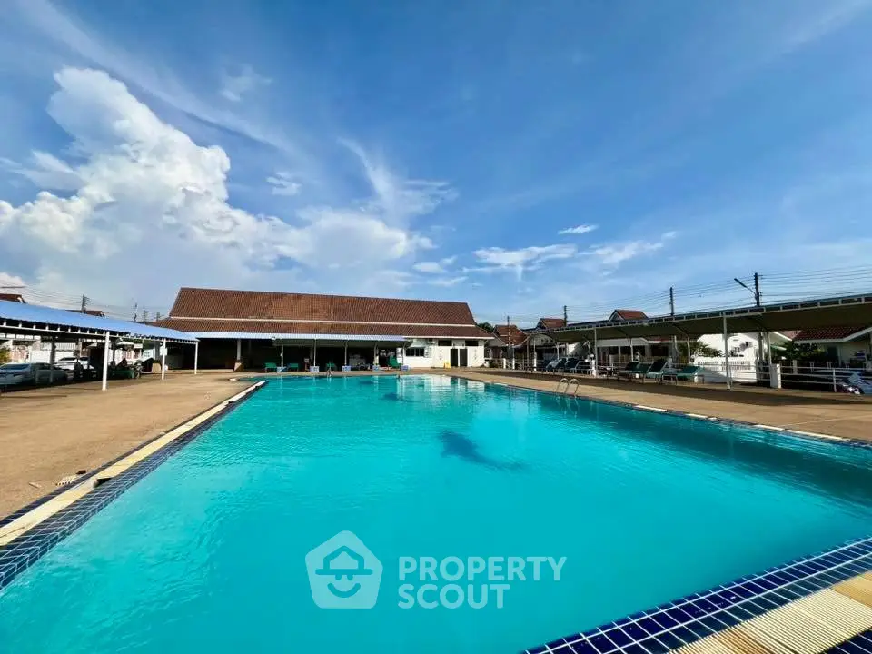 Spacious outdoor pool area with clear blue sky, perfect for relaxation and leisure.