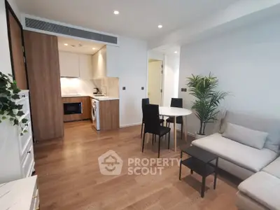 Modern open-plan living room with stylish kitchen and cozy seating area, featuring wooden flooring and contemporary decor.