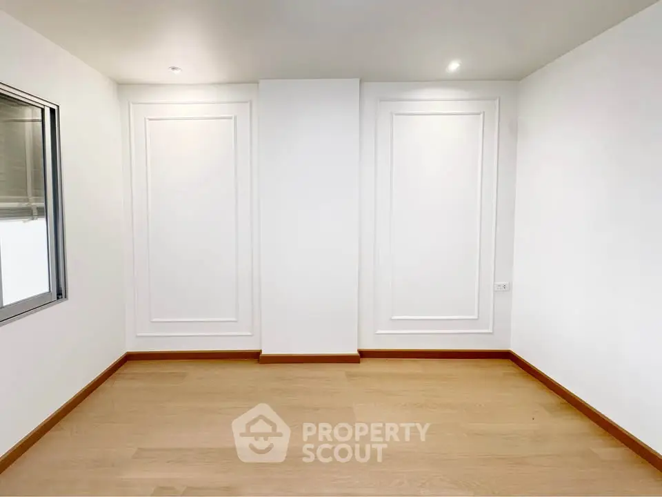 Minimalist empty room with wooden flooring and white walls, perfect for customization.