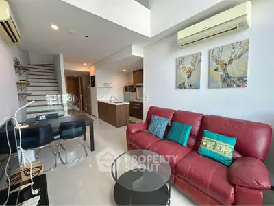 Modern living room with red sofa, dining area, and stylish kitchen in open layout apartment.