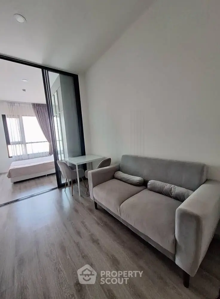 Modern apartment interior with cozy living room and bedroom view, featuring sleek furniture and natural light.