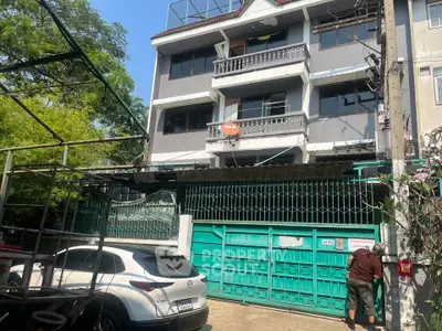 Charming multi-story residential building with gated entrance and parked car, ideal for urban living.