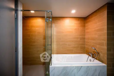 Modern bathroom with elegant bathtub and glass shower enclosure.