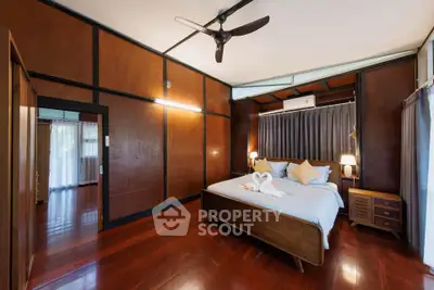 Spacious bedroom with wooden accents and elegant decor in a modern home.
