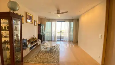 Spacious living room with elegant decor and large window offering natural light and balcony access.