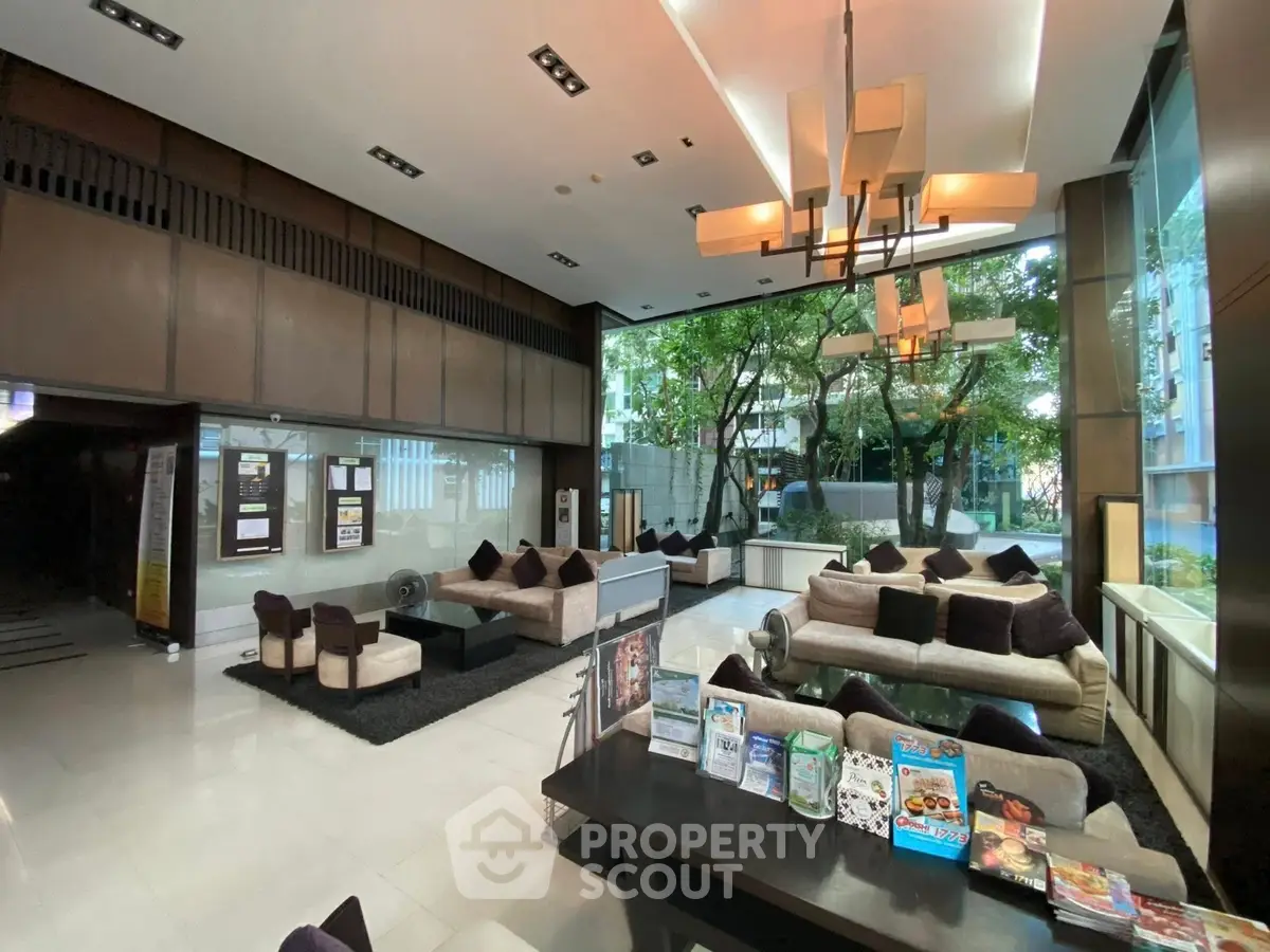 Luxurious modern lobby with plush seating and large windows overlooking greenery, perfect for relaxation.