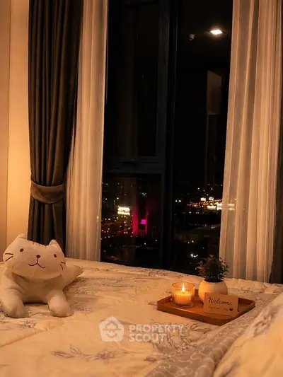 Cozy bedroom with city view, plush cat pillow, and warm candlelight ambiance.