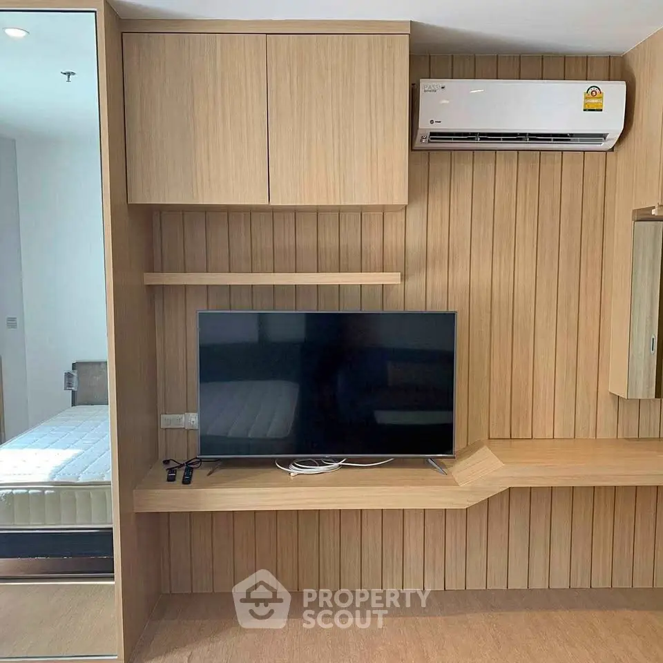 Modern bedroom with built-in wooden TV unit and air conditioning