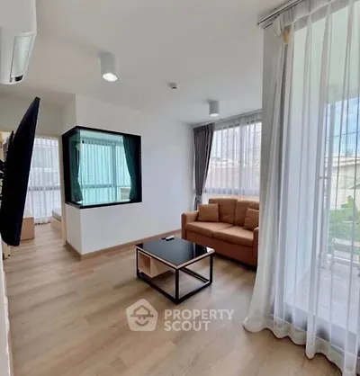 Modern living room with large windows and stylish furniture in a bright apartment.