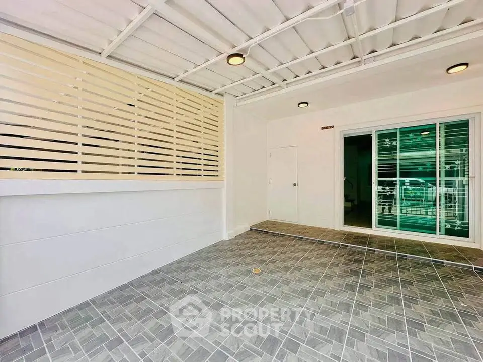 Spacious covered parking area with modern tiled flooring and sliding glass doors.