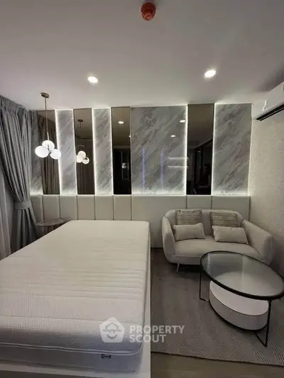 Modern bedroom with stylish decor, featuring a cozy sofa and elegant lighting, perfect for relaxation.