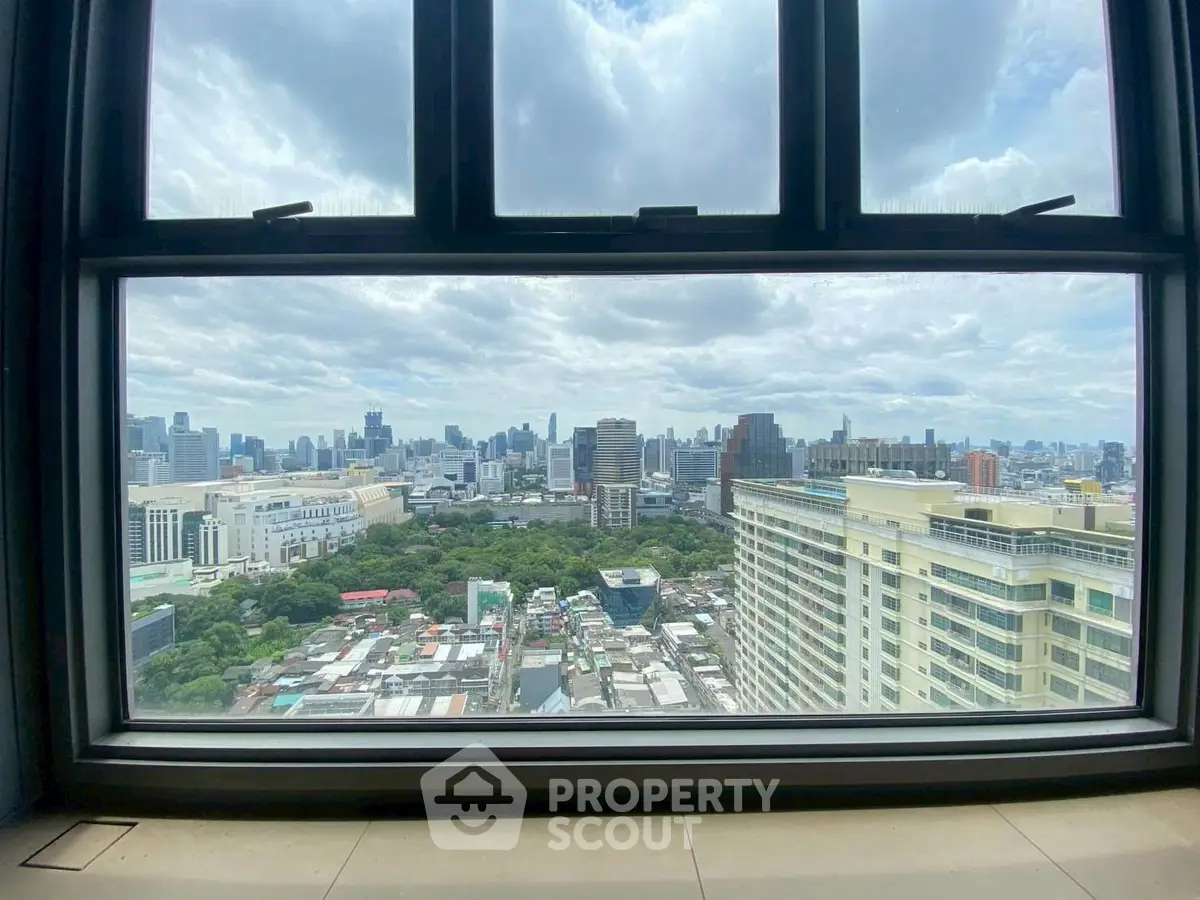 Stunning cityscape view from high-rise window, showcasing urban skyline and greenery.
