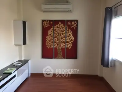 Minimalist living room with wooden flooring and tree artwork on wall