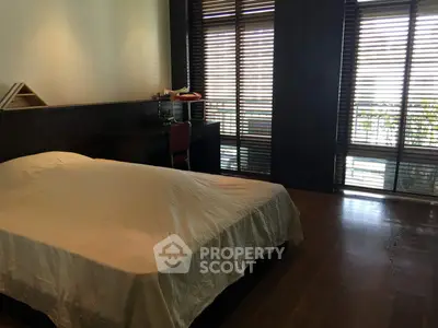 Spacious bedroom with wooden flooring and large windows offering natural light.