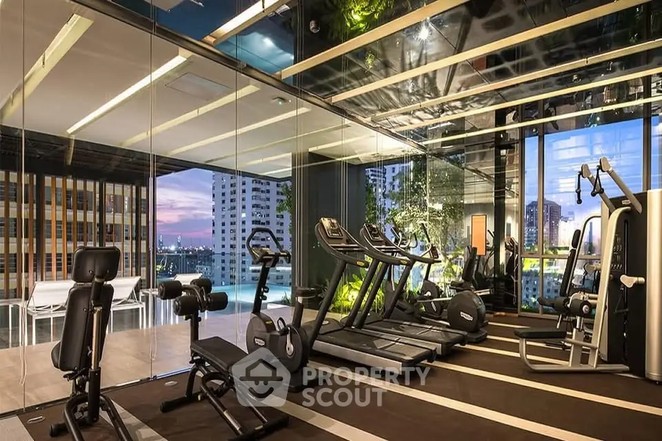 Luxurious gym with modern equipment and stunning city view in upscale residential building.