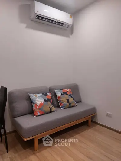 Cozy living room with modern sofa and air conditioning unit, perfect for relaxation.