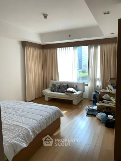 Bright bedroom with wooden flooring and large window in modern apartment