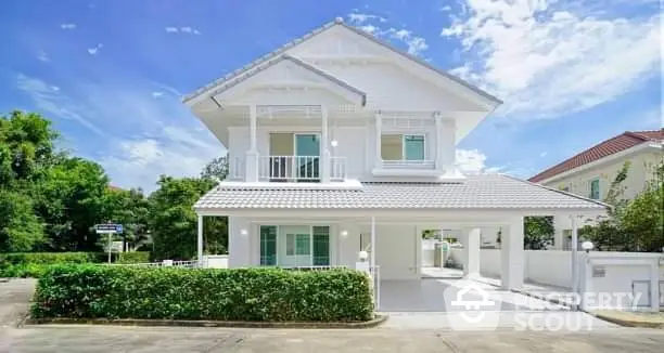 Stunning white two-story house with lush greenery and clear blue sky