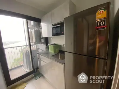 Modern compact kitchen with stainless steel appliances and balcony view