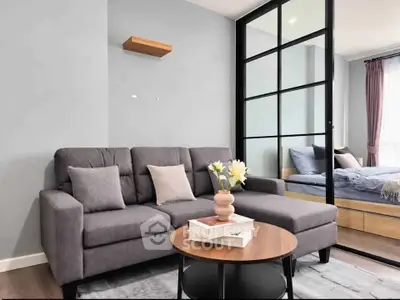 Modern living room with stylish gray sofa and sliding glass doors leading to a cozy bedroom.