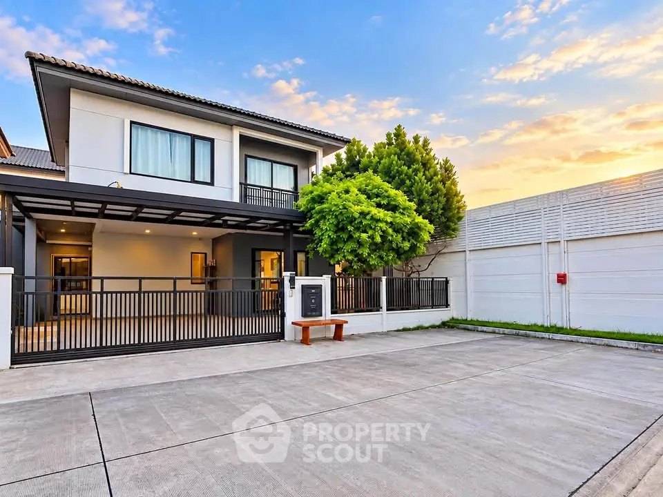 Modern two-story house with spacious driveway and lush greenery at sunset.