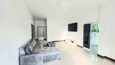 Spacious modern living room with sleek gray sofa and wall-mounted TV, perfect for relaxation.