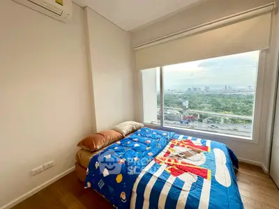 Bright bedroom with large window offering stunning city view and colorful bedding.