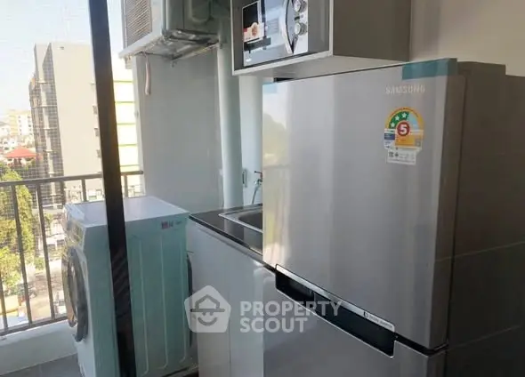 Modern apartment balcony with washing machine and fridge, offering urban convenience and functionality.