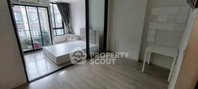 Modern apartment with glass partition and wooden flooring, featuring a compact bedroom and study area.