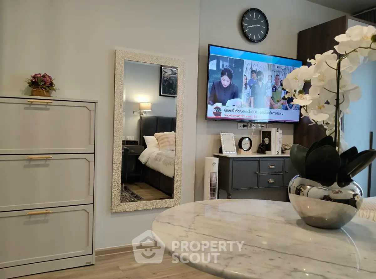 Modern living room with elegant decor and wall-mounted TV, featuring a stylish mirror and chic furniture.