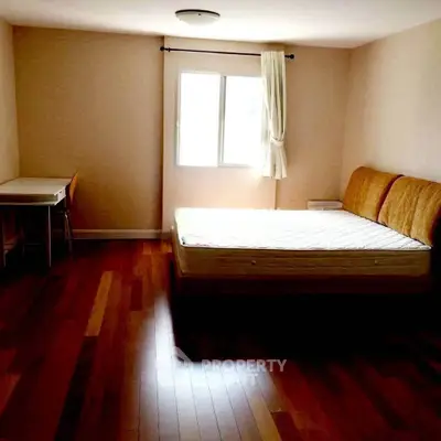 Spacious bedroom with wooden flooring and natural light