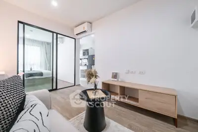 Modern living room with open layout and stylish decor, featuring a view into a cozy bedroom.