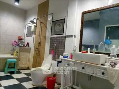 Spacious bathroom with modern fixtures and checkered flooring, featuring a large mirror and ample storage space.