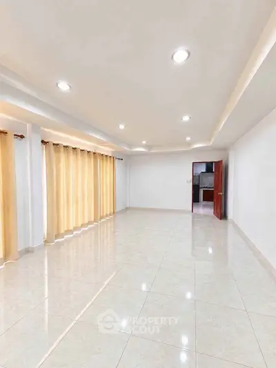 Spacious and bright living room with modern recessed lighting and large windows.