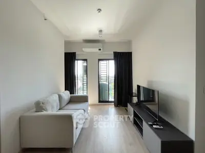 Modern living room with sleek furniture and large windows offering city views.