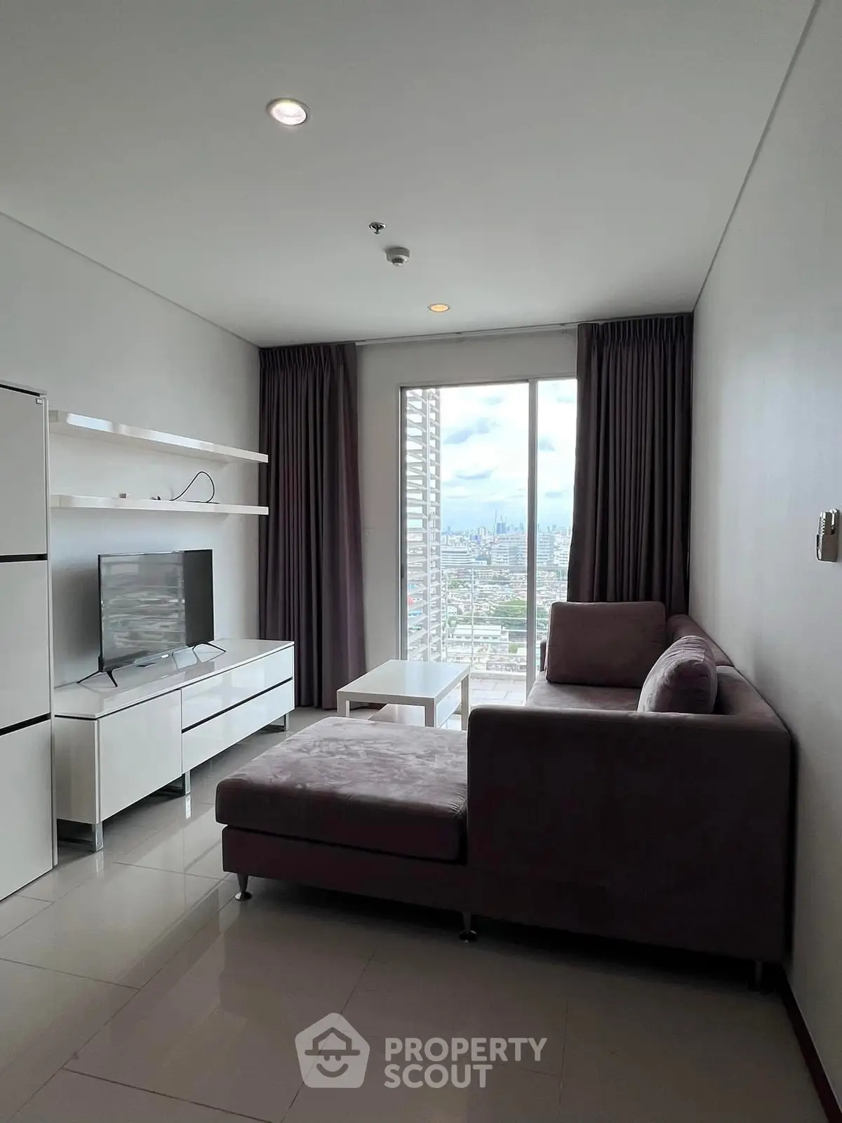 Modern living room with city view, featuring sleek furniture and large window for natural light.