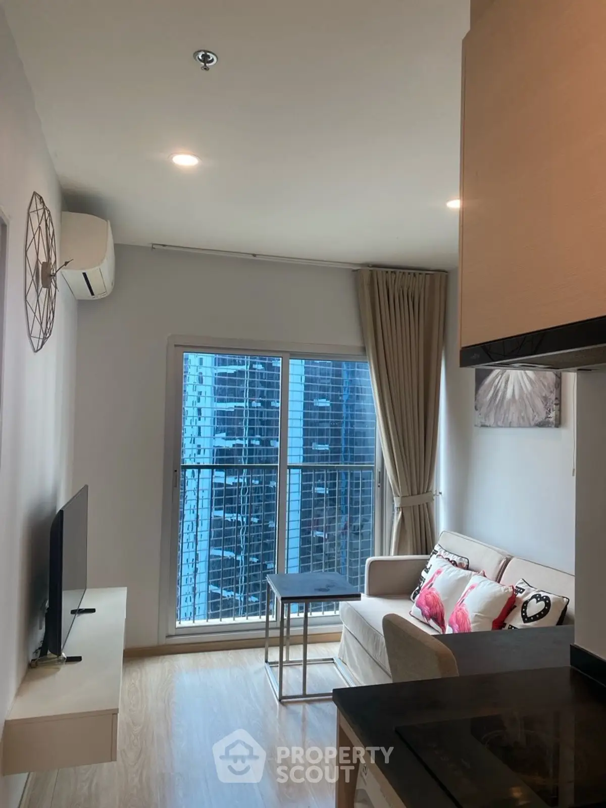 Modern living room with city view, featuring cozy sofa and wall-mounted TV.