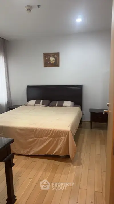 Spacious bedroom with wooden flooring and elegant decor in modern apartment.