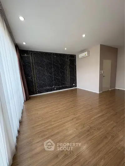 Spacious empty room with elegant wood flooring and modern wall design