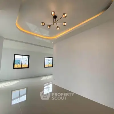 Spacious modern living room with stylish ceiling lights and large windows.