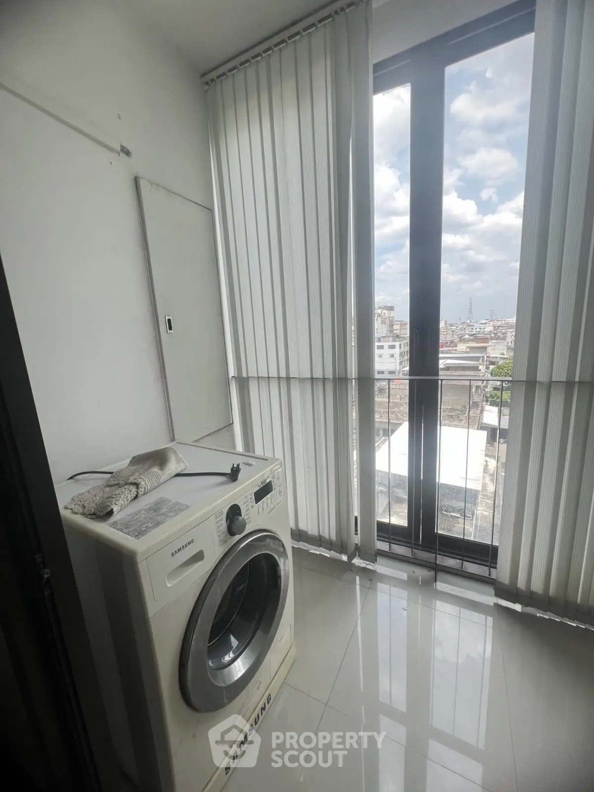 Modern laundry area with washing machine and city view through large windows.