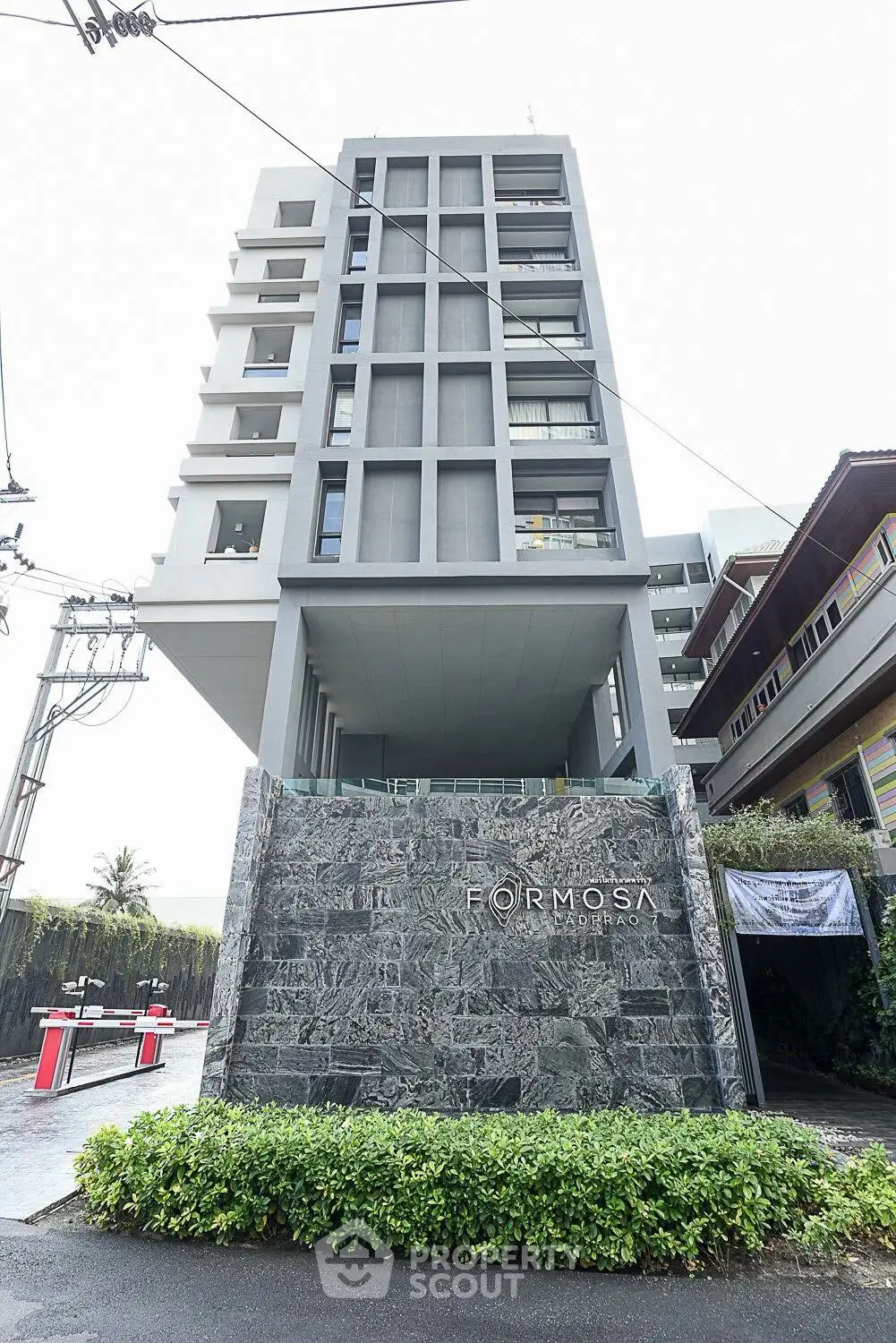 Modern high-rise building with sleek architecture and stone facade in urban setting.