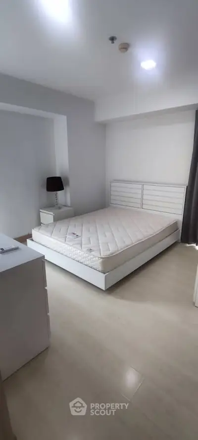 Spacious bedroom with modern white furniture and ample natural light