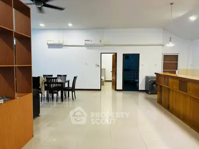 Spacious open-plan living area with dining set and modern kitchen bar