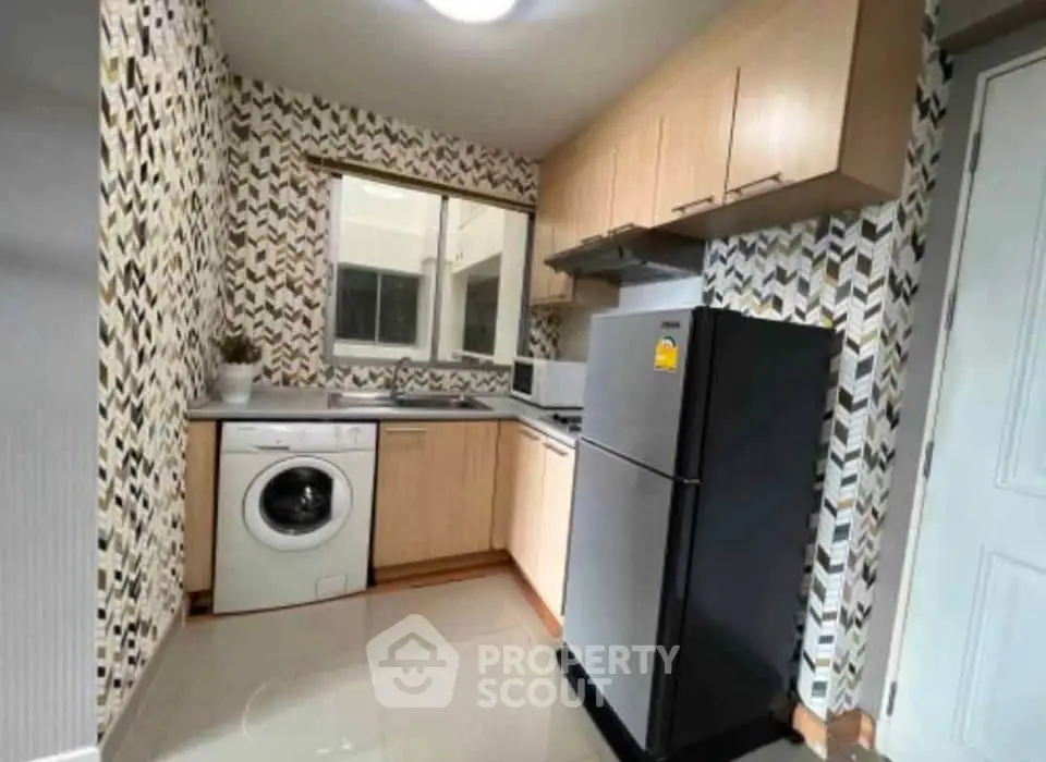 Modern kitchen with stylish backsplash, washing machine, and sleek appliances.