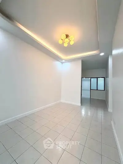 Spacious empty room with modern lighting and tiled flooring, perfect for customization.