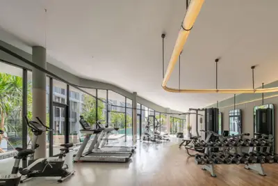 Spacious modern gym with state-of-the-art equipment and pool view in luxury residential complex.